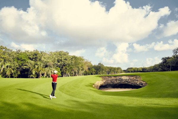 golfer tees off across cenote hole at mayakoba